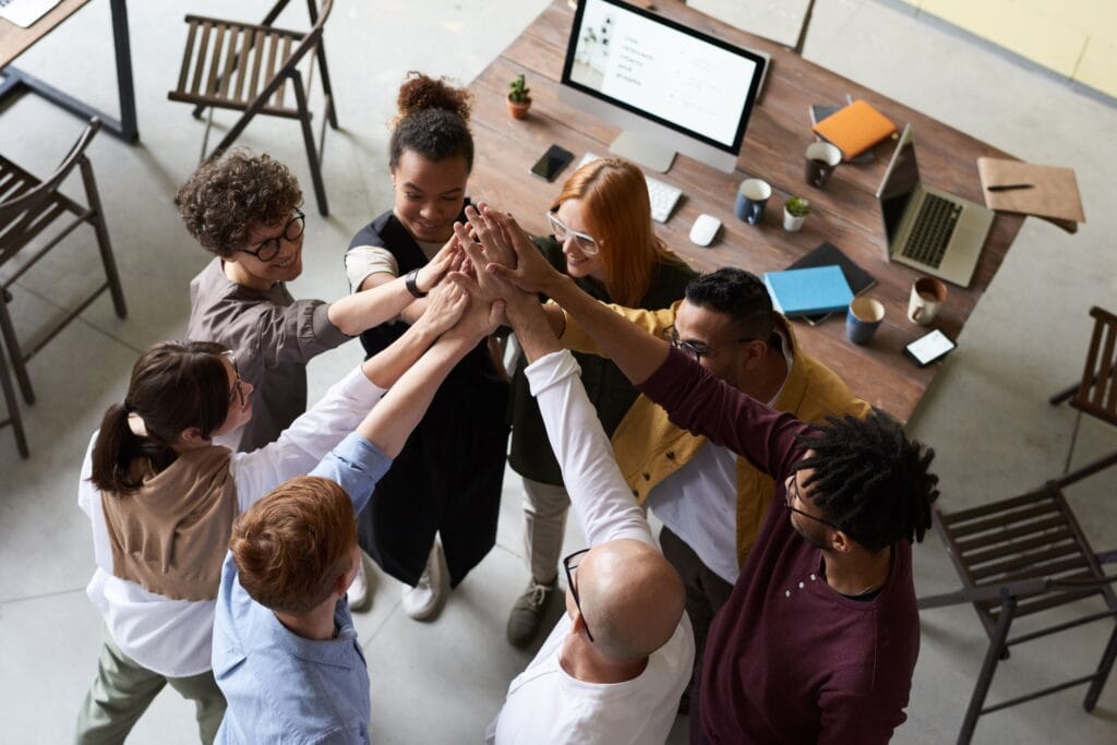 Diverse office team sharing a high five — corporate and team yoga wellness from Missing Peace Yoga.